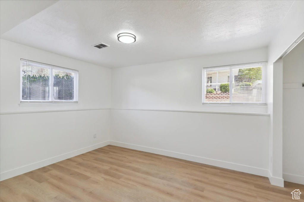 Spare room with visible vents, a textured ceiling, light wood-style floors, and a wealth of natural light