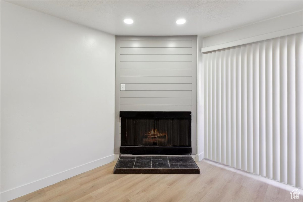 Room details with baseboards, a fireplace with raised hearth, recessed lighting, and wood finished floors