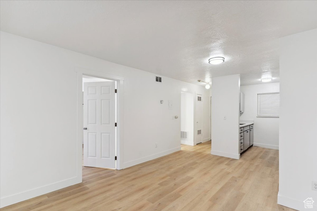 Unfurnished living room with baseboards, visible vents, and light wood-style floors