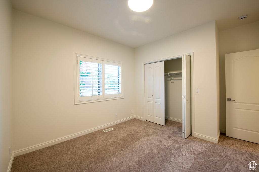 Unfurnished bedroom with carpet floors, baseboards, a closet, and visible vents