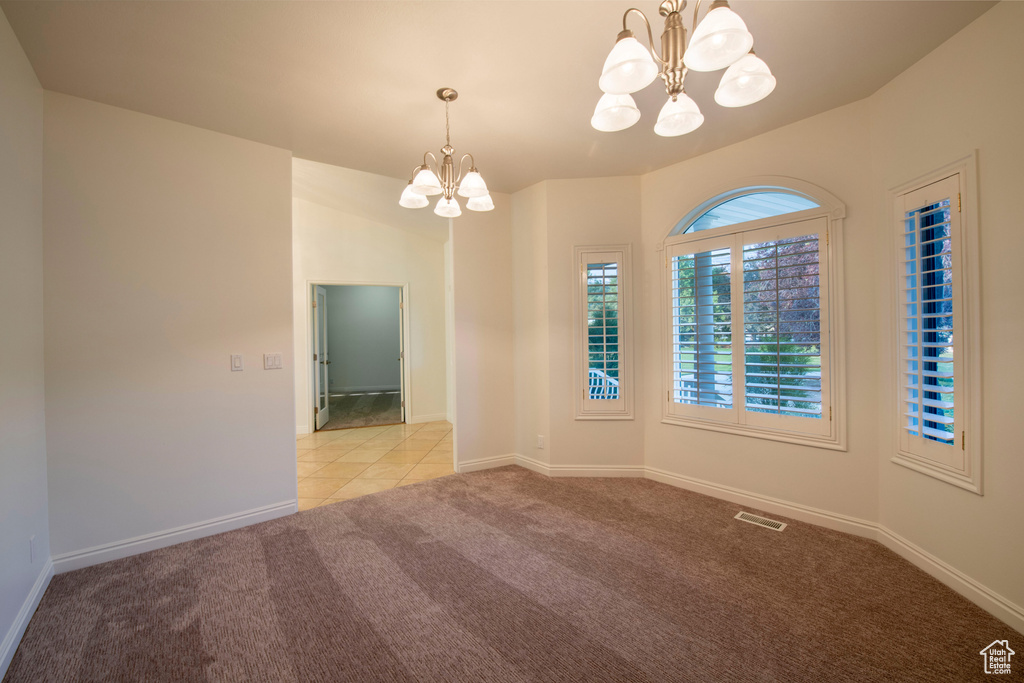 Tiled spare room with an inviting chandelier, carpet, baseboards, and visible vents