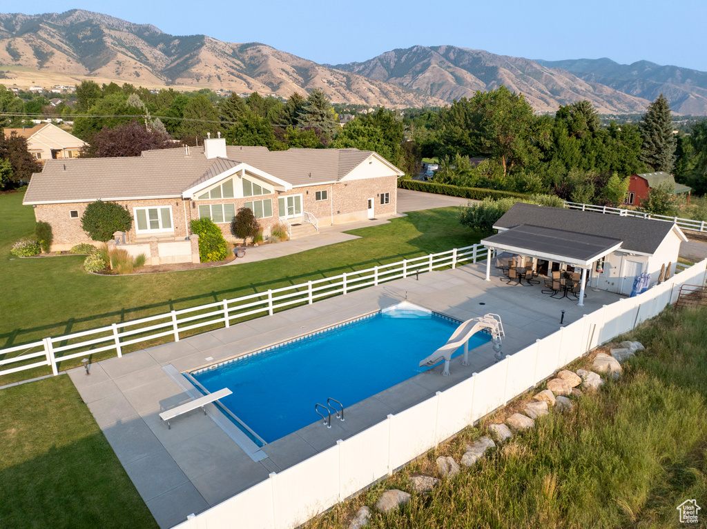 View of pool with a water slide, a fenced in pool, a fenced backyard, a patio, and a yard