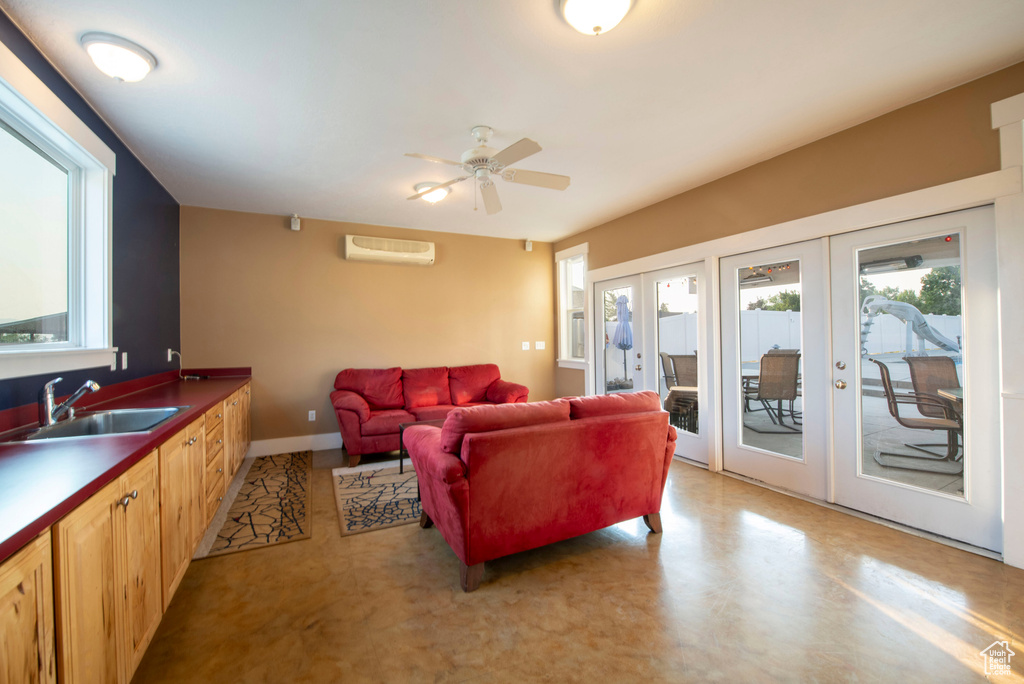 Living area with baseboards, ceiling fan, a wall mounted AC, and french doors