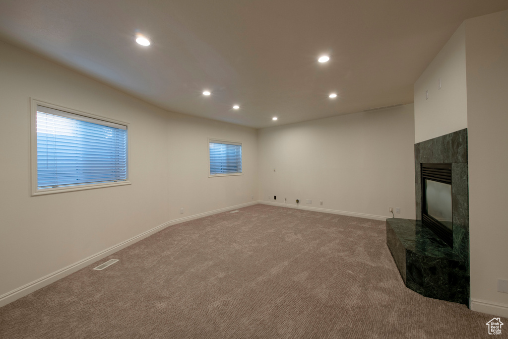 Unfurnished living room featuring visible vents, carpet floors, baseboards, recessed lighting, and a premium fireplace