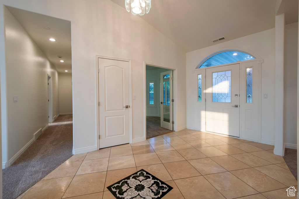 Foyer entrance featuring visible vents, baseboards, light tile patterned floors, and high vaulted ceiling