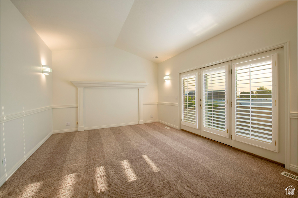 Unfurnished room with visible vents, baseboards, carpet, and lofted ceiling