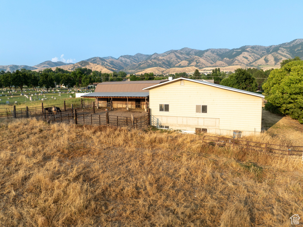 View of side of home featuring an exterior structure, a rural view, metal roof, a mountain view, and an outbuilding