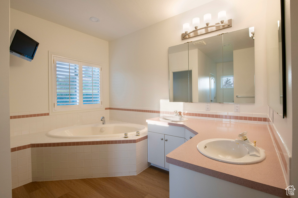 Full bathroom with a garden tub, a sink, wood finished floors, and double vanity