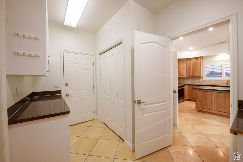 Hallway with recessed lighting, a sink, and light tile patterned floors