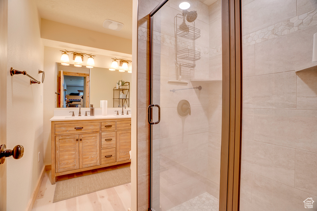 Bathroom featuring double vanity, a shower stall, and a sink