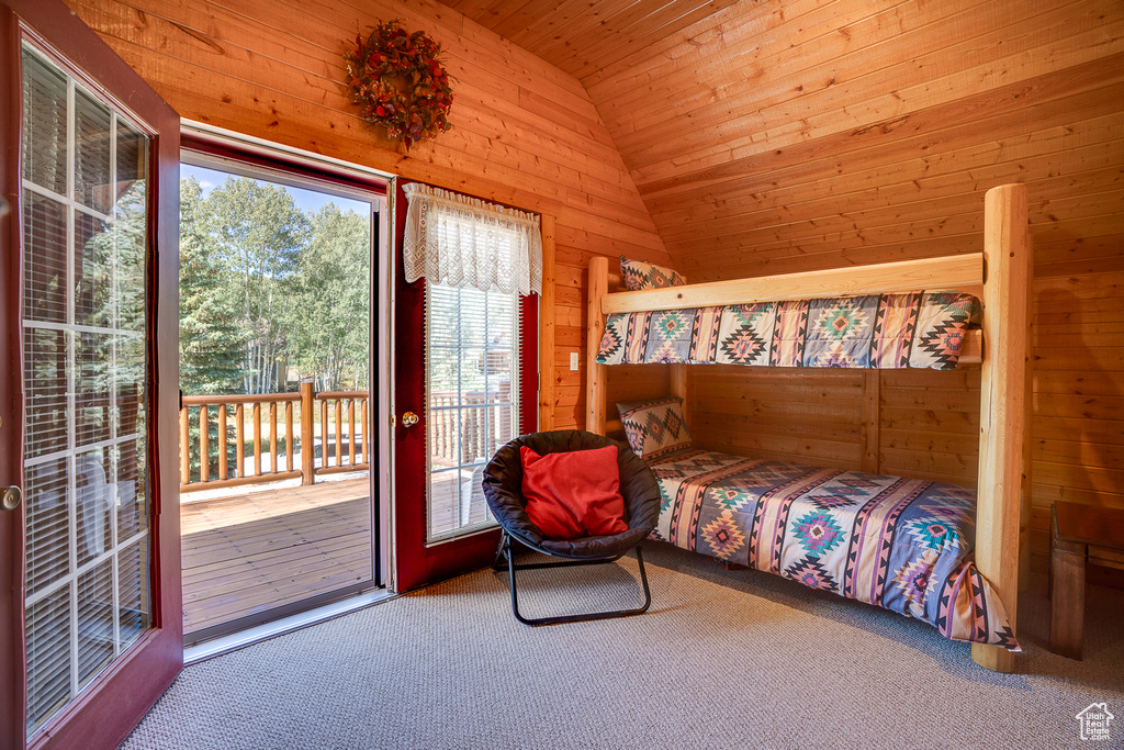 Bedroom with access to exterior, wood walls, lofted ceiling, and carpet floors