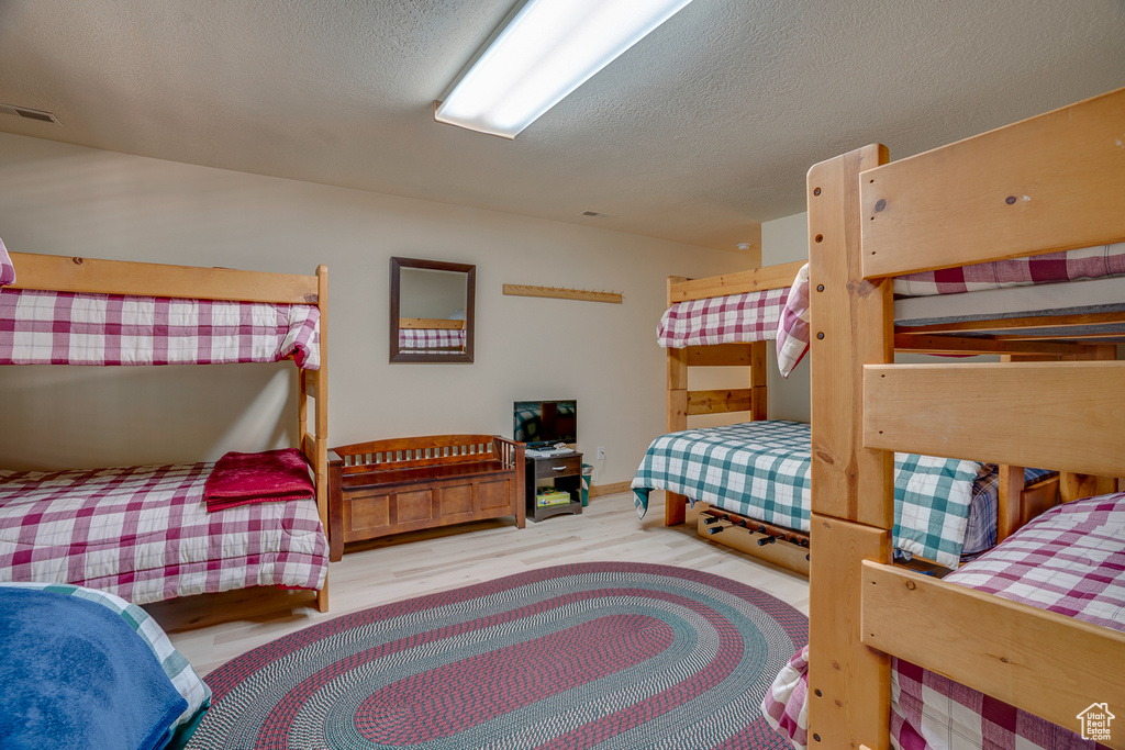 Bedroom featuring a textured ceiling, visible vents, wood finished floors, and baseboards