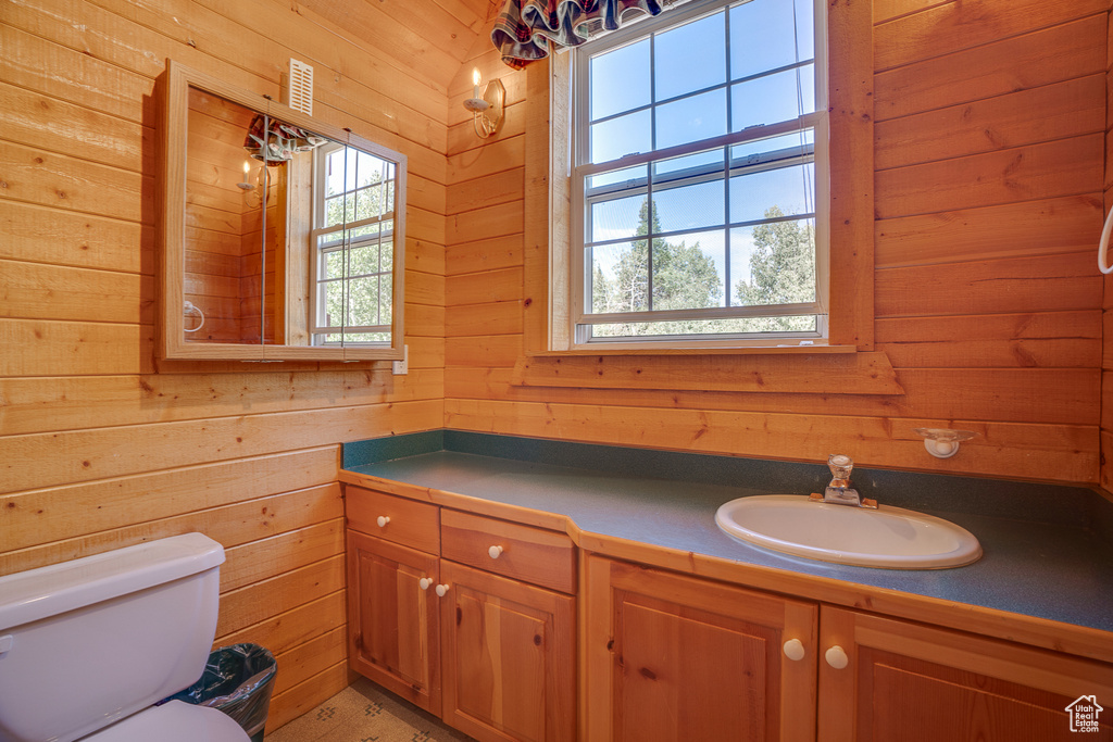 Bathroom featuring toilet, wooden walls, vanity, and visible vents