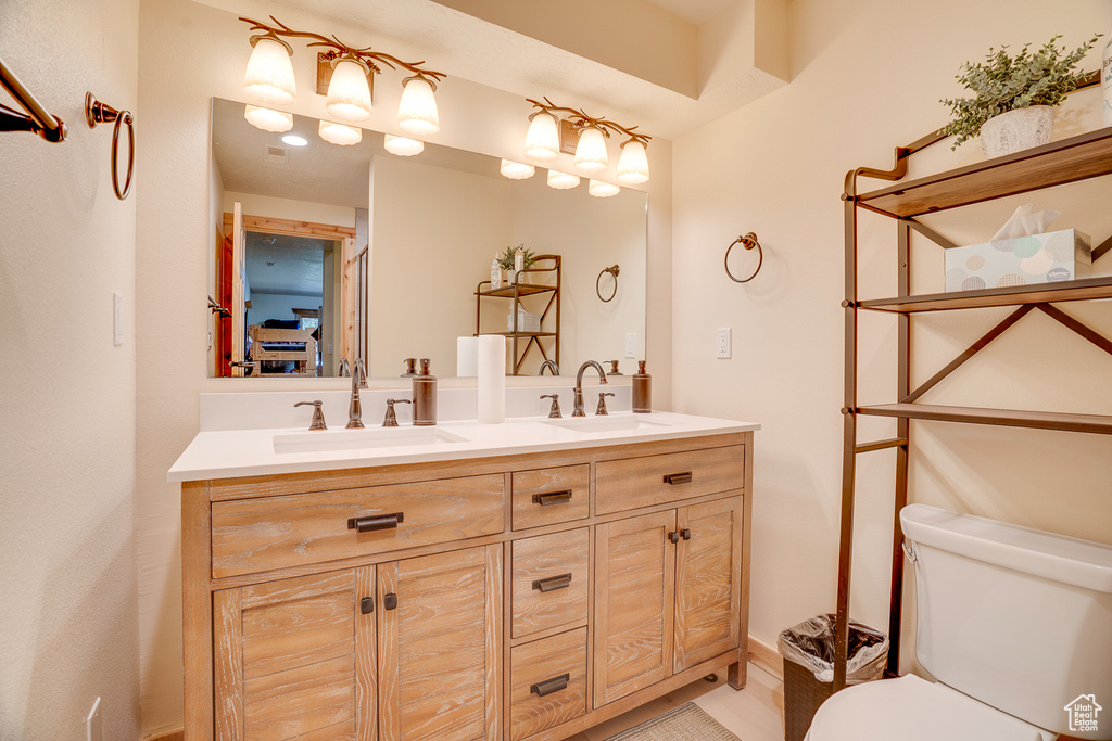 Bathroom featuring a sink, double vanity, and toilet