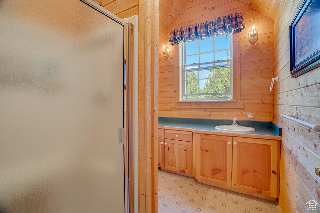 Bathroom featuring a shower stall, wood walls, and vanity