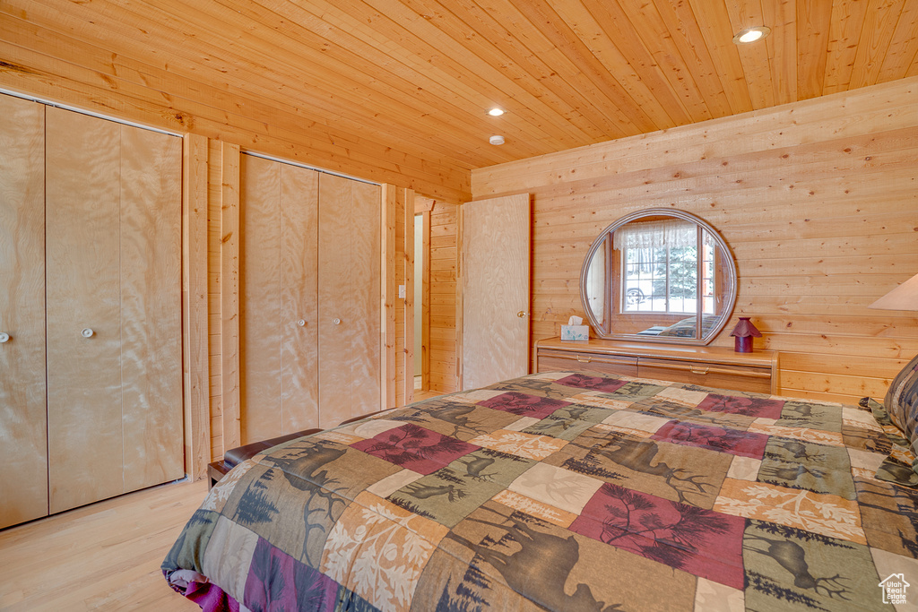 Bedroom featuring recessed lighting, wood ceiling, wooden walls, two closets, and wood finished floors
