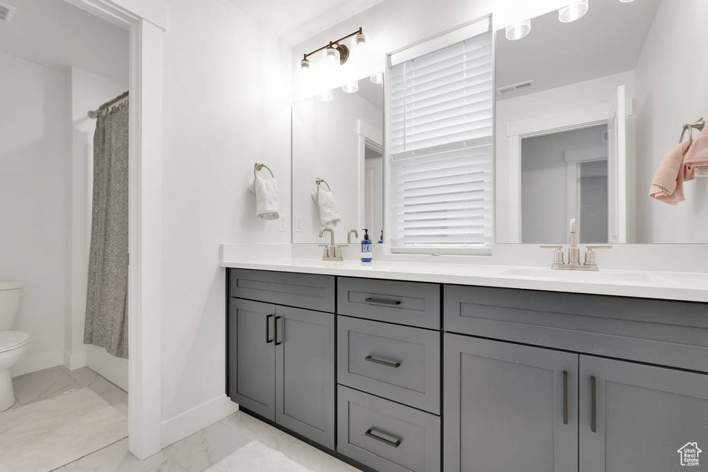 Full bath featuring toilet, marble finish floor, baseboards, and a sink