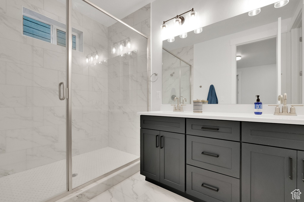 Bathroom with a shower stall, marble finish floor, double vanity, and a sink