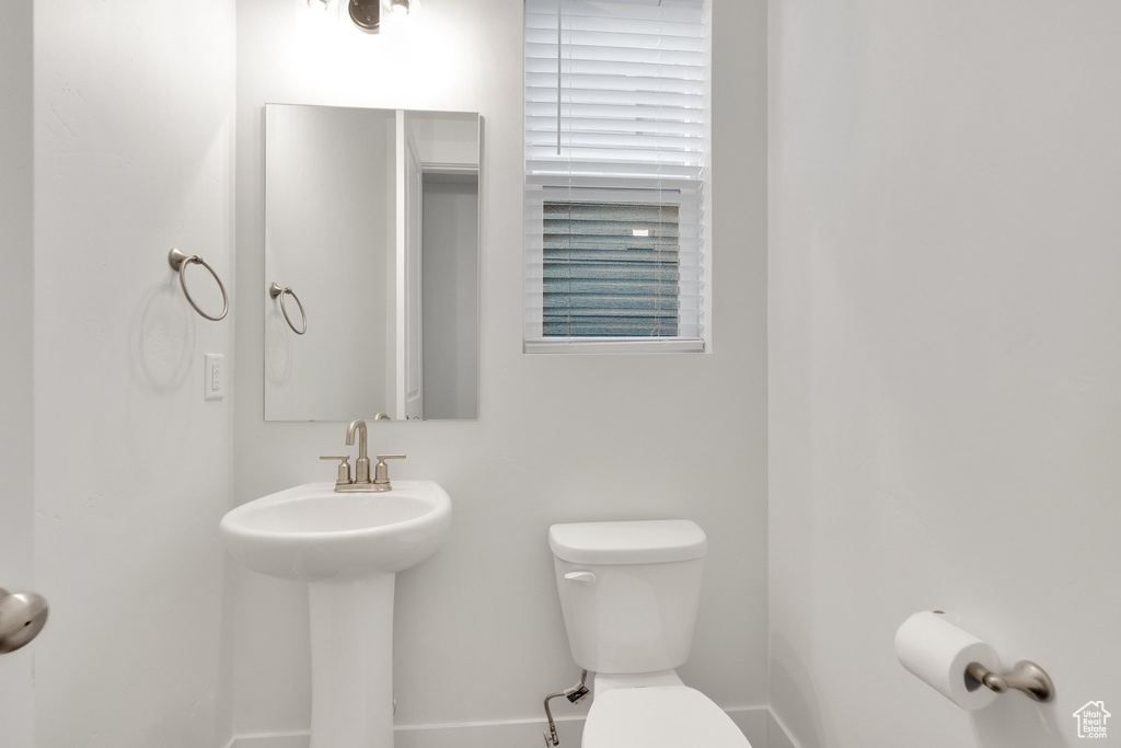 Bathroom featuring toilet, baseboards, and a sink