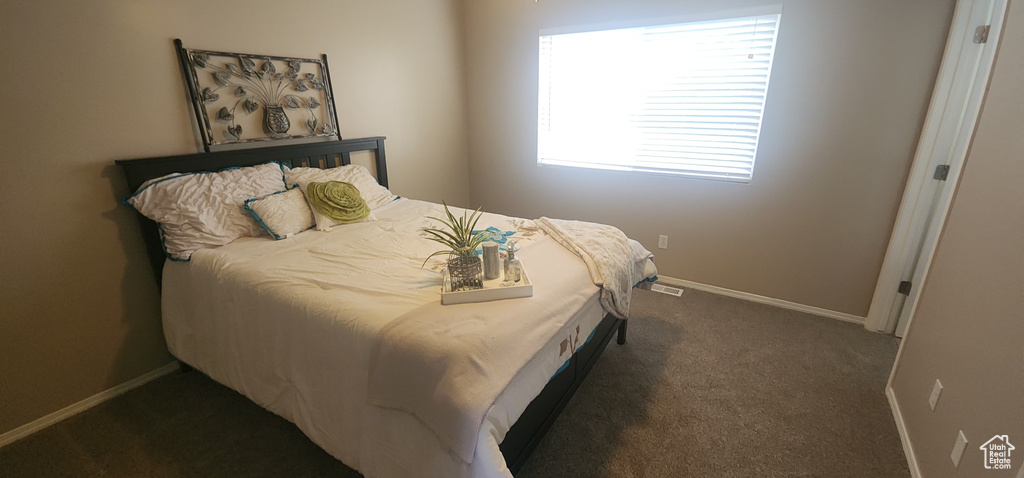 Bedroom featuring baseboards, dark carpet, and visible vents