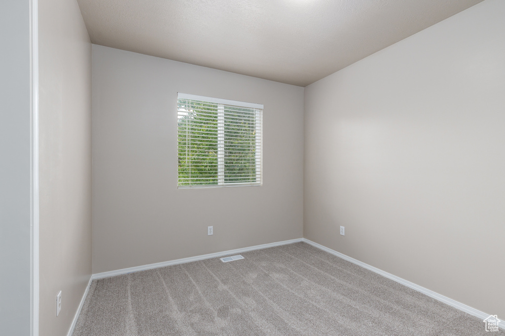 Spare room featuring light colored carpet and baseboards