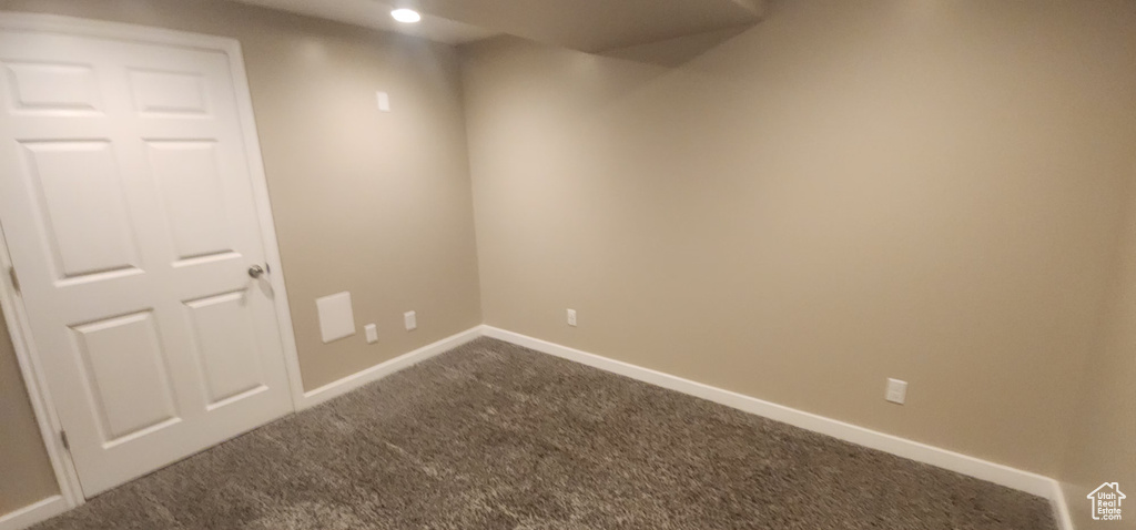 Empty room featuring baseboards and dark carpet
