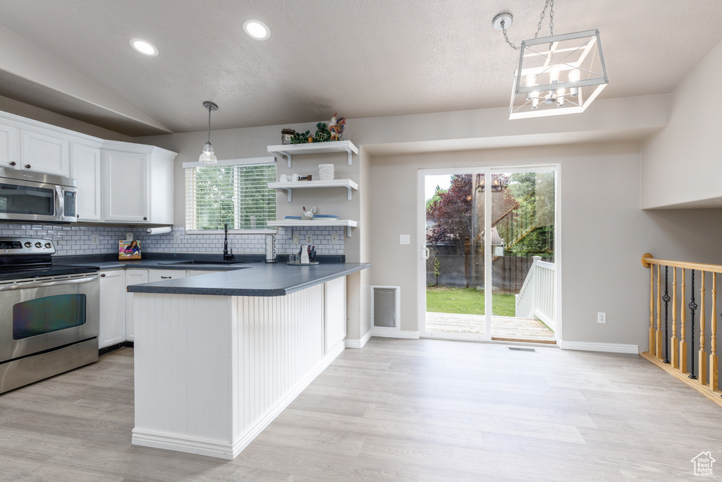 Kitchen with appliances with stainless steel finishes, a sink, dark countertops, decorative backsplash, and plenty of natural light