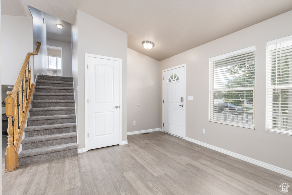 Entrance foyer featuring light wood-style floors, baseboards, and stairs