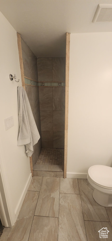 Full bath featuring a tile shower, toilet, baseboards, and visible vents