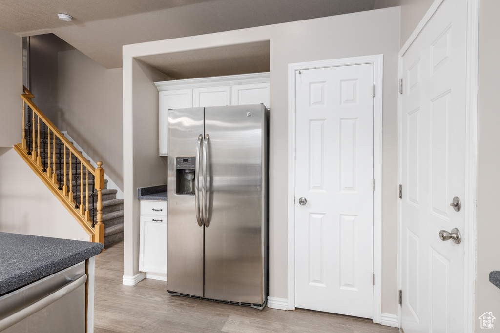 Kitchen featuring appliances with stainless steel finishes, light wood-type flooring, white cabinets, and baseboards