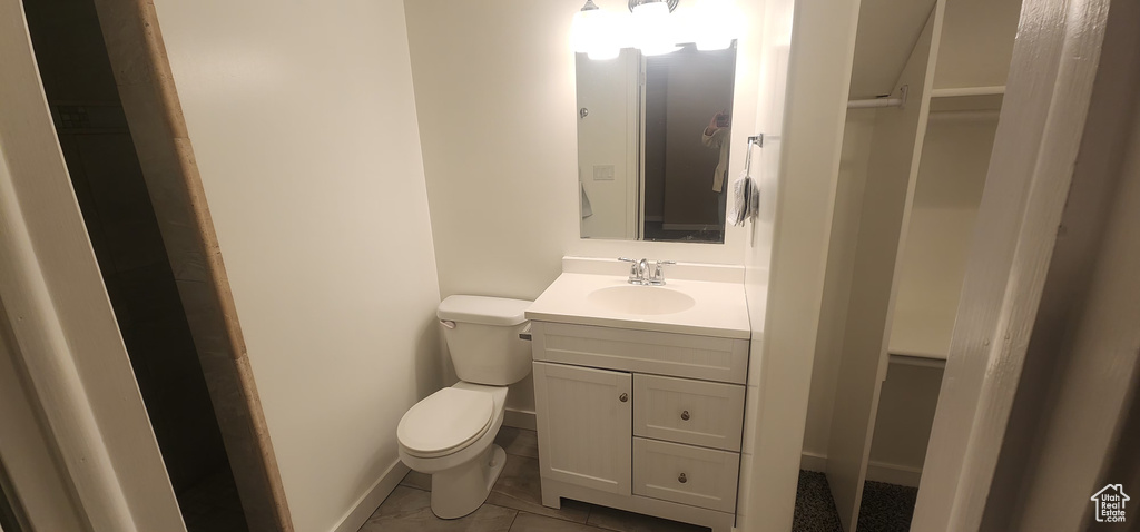 Bathroom featuring toilet, baseboards, and vanity