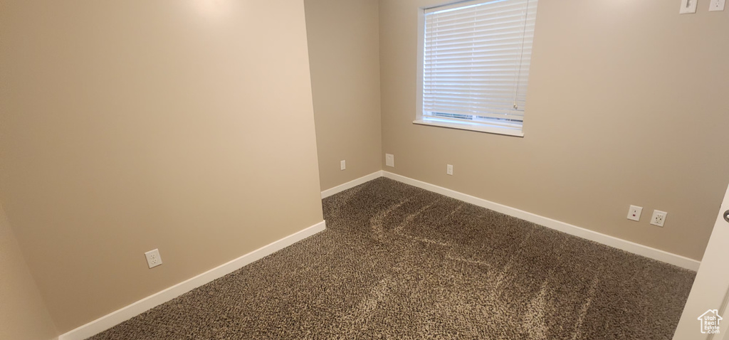 Empty room with baseboards and dark carpet