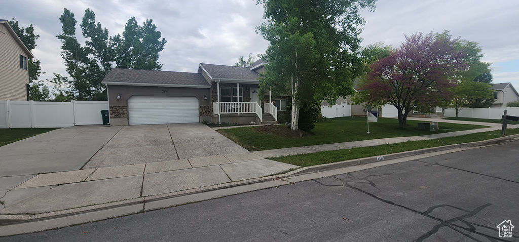 View of front of house with fence, an attached garage, driveway, stucco siding, and a front yard