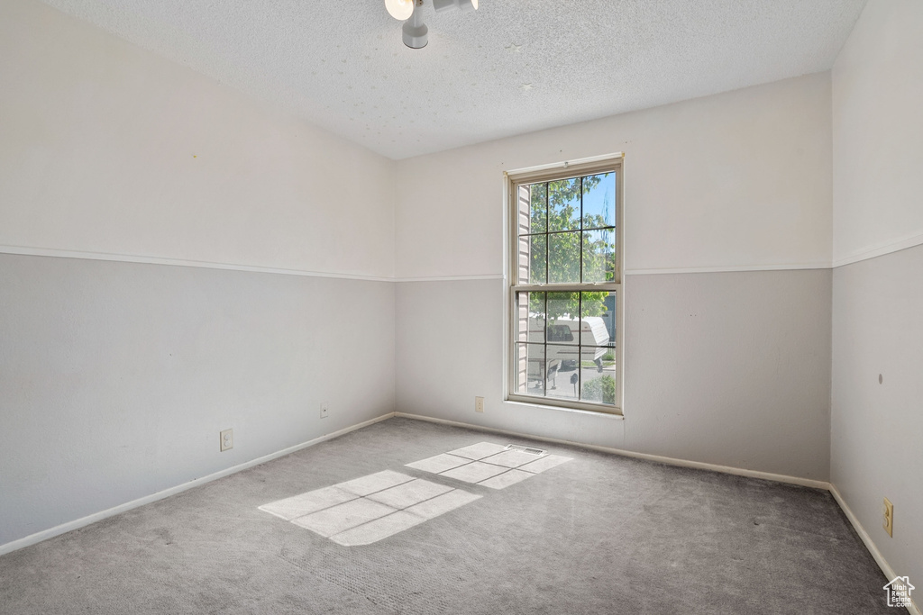 Carpeted empty room featuring baseboards and a textured ceiling