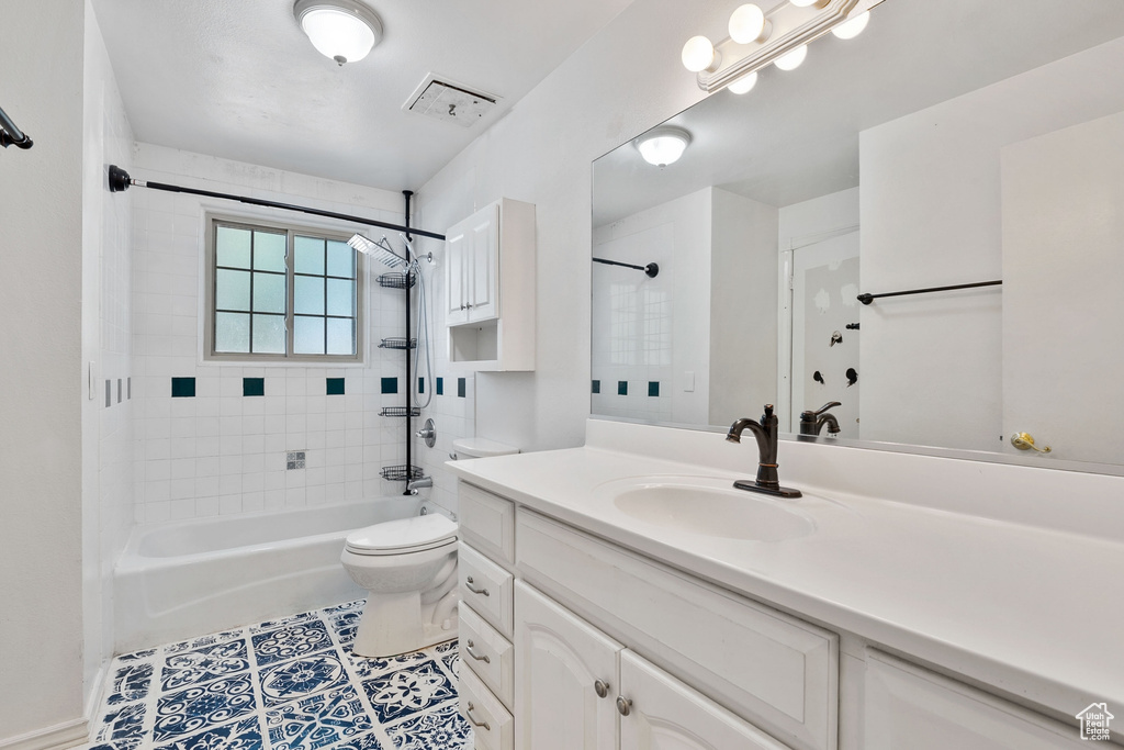 Bathroom featuring toilet, visible vents, tile patterned floors, vanity, and washtub / shower combination