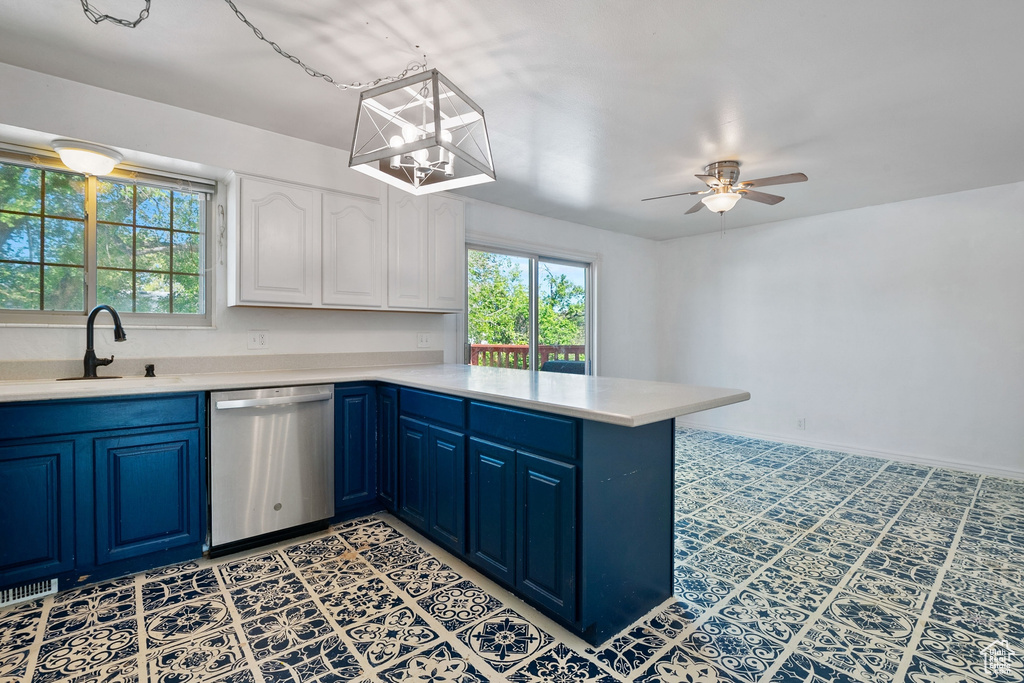 Kitchen with a peninsula, light countertops, a sink, dishwasher, and blue cabinets