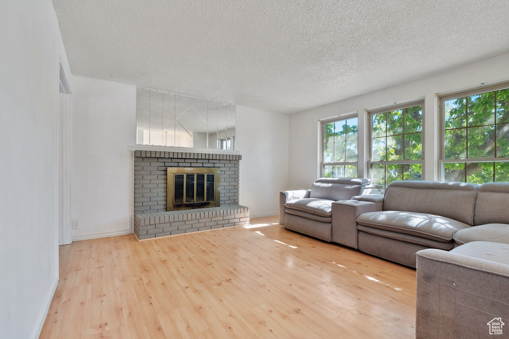 Living area featuring a textured ceiling, baseboards, wood finished floors, and a fireplace