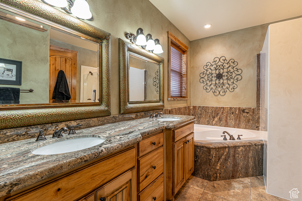 Bathroom featuring double vanity, a bath, tile patterned flooring, and a sink