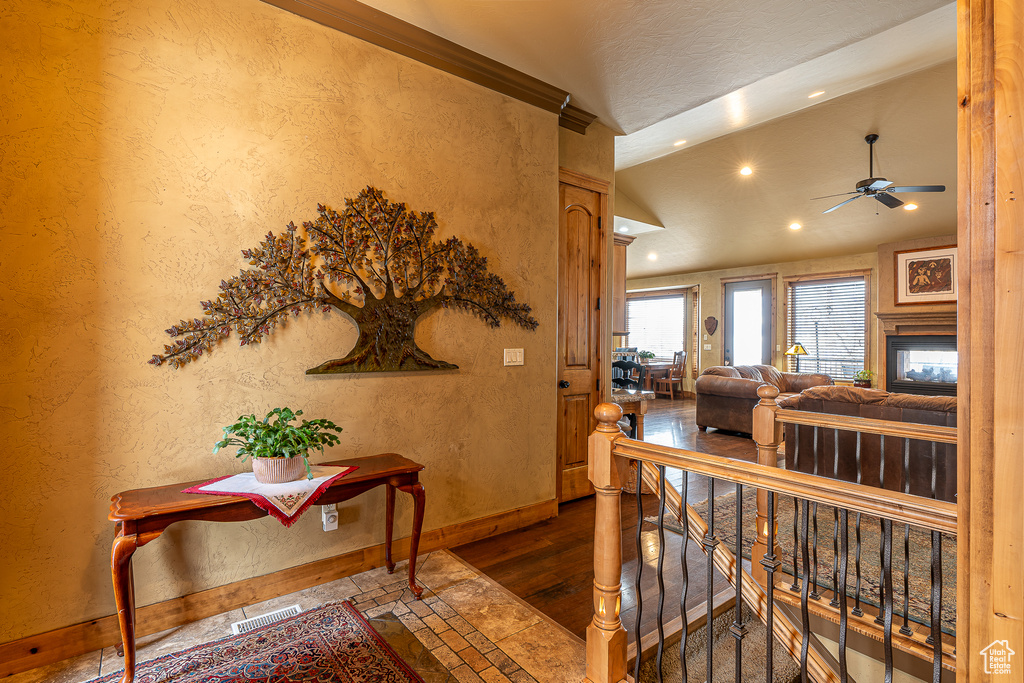 Corridor with visible vents, baseboards, a textured wall, lofted ceiling, and recessed lighting