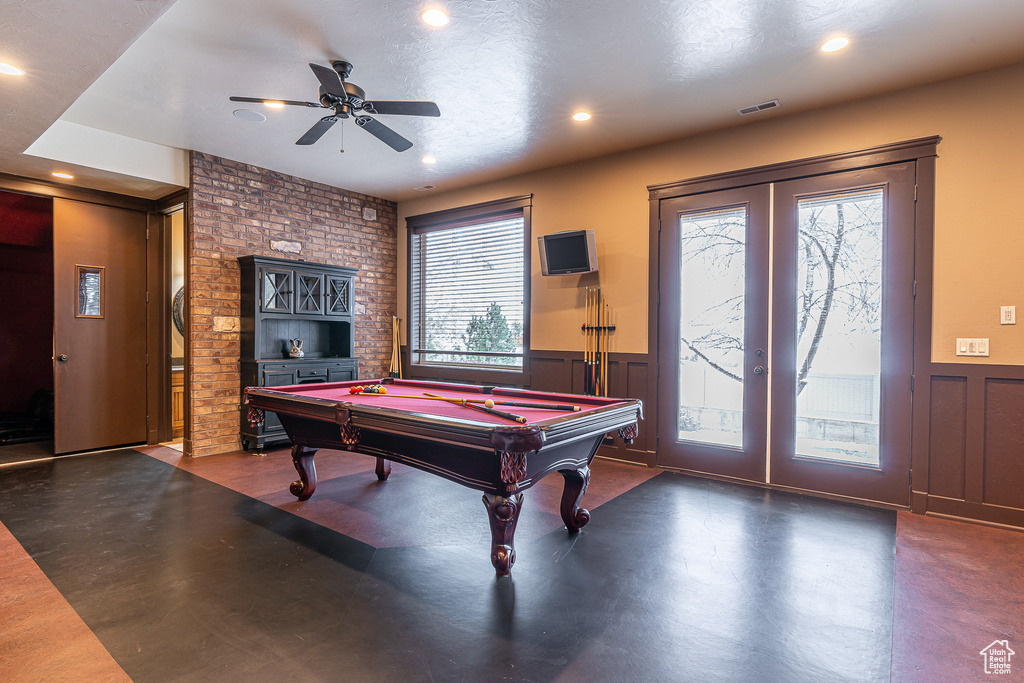 Recreation room featuring french doors, finished concrete floors, pool table, a ceiling fan, and wainscoting