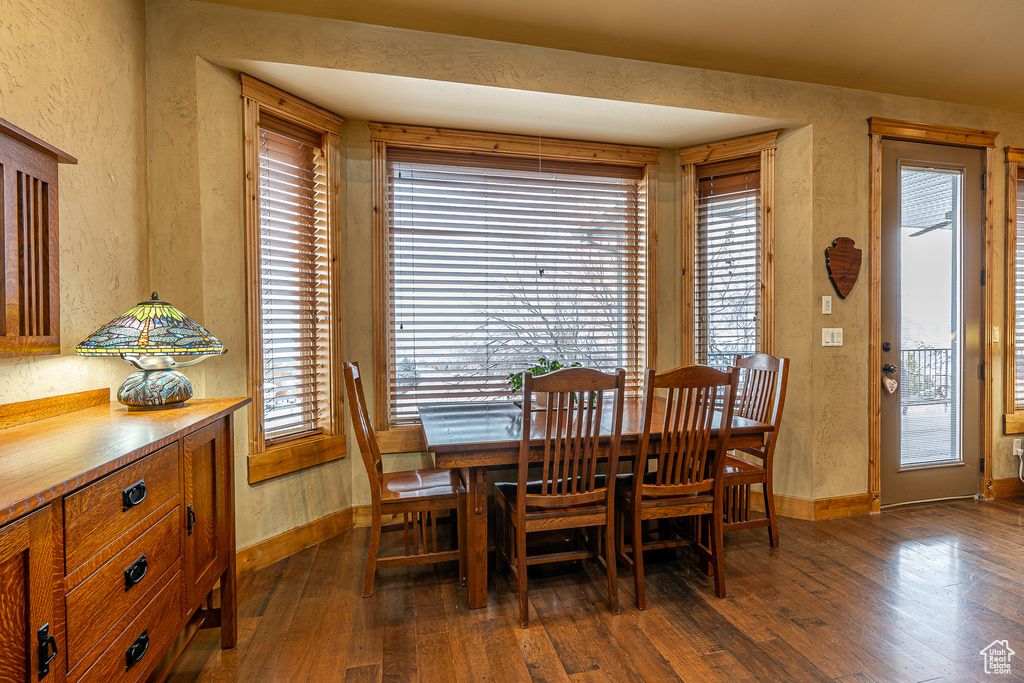 Dining room featuring a textured wall, baseboards, and dark wood-type flooring