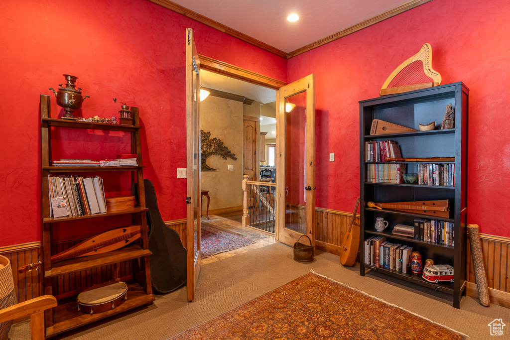 Living area featuring ornamental molding, carpet flooring, an upstairs landing, and wainscoting