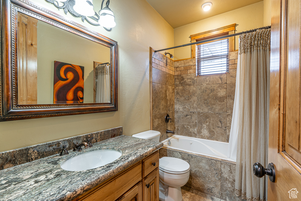 Bathroom with toilet, vanity, and tiled shower / bath
