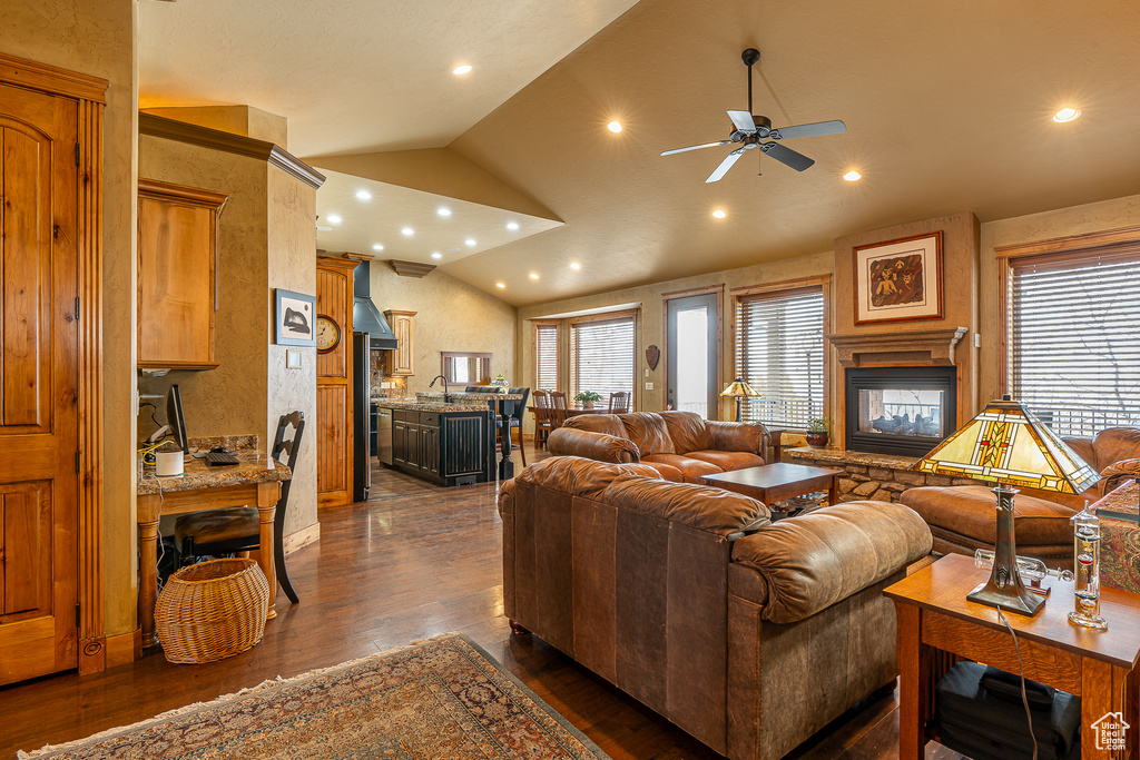 Living area featuring lofted ceiling, dark wood-type flooring, recessed lighting, a ceiling fan, and a multi sided fireplace