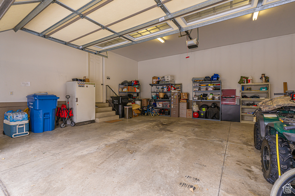 Garage featuring freestanding refrigerator and a garage door opener