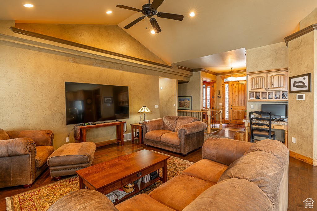 Living room featuring lofted ceiling, wood-type flooring, a ceiling fan, and a textured wall