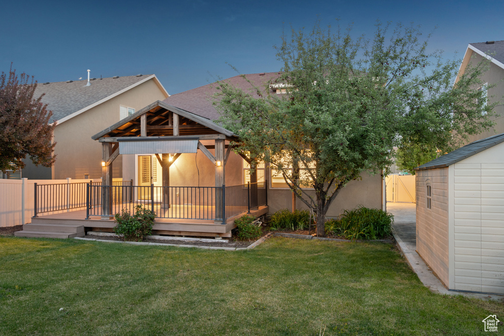 Back of property with a yard, a deck, a fenced backyard, and stucco siding
