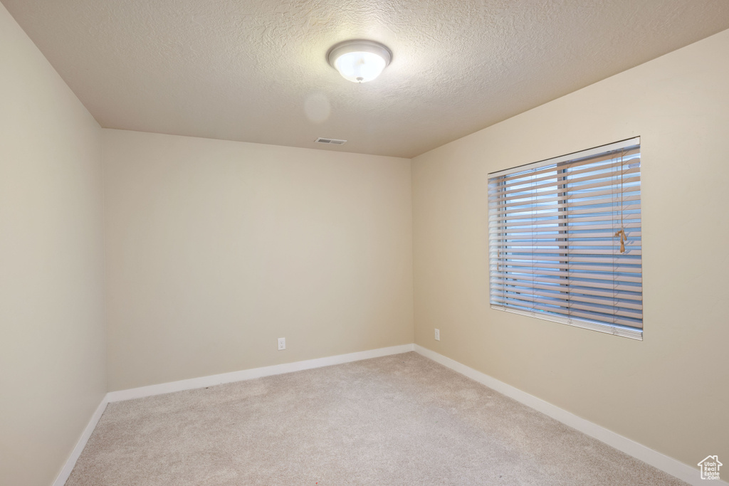 Unfurnished room featuring carpet floors, a textured ceiling, baseboards, and visible vents