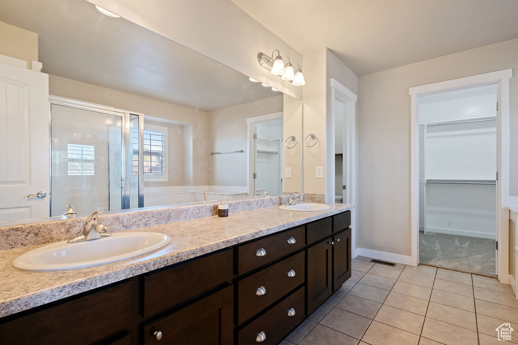 Bathroom with double vanity, a sink, tile patterned flooring, and a stall shower