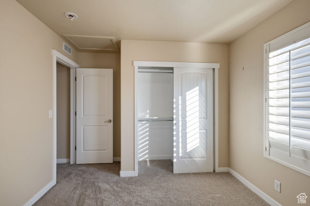 Unfurnished bedroom with carpet floors, multiple windows, attic access, and visible vents